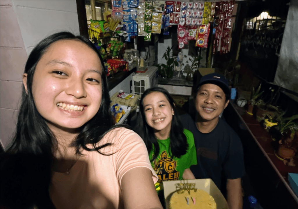 Papa Lenslo smiling with Chloe, also known as Ate Lottie, and her younger sister Jashel Kaye in a joyful family selfie with a birthday cake.